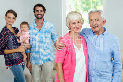 Happy senior couple with family in background