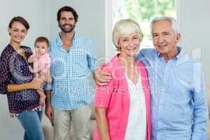 Happy senior couple with family in background