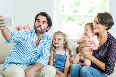 Family making faces while taking selfie on sofa