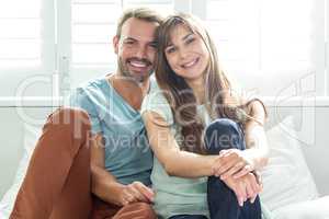 Happy couple relaxing on bed against window