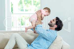 Father smiling while playing with son on sofa