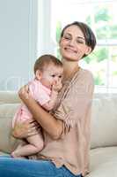 Mother carrying son while sitting on sofa