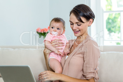 Mother smiling while carrying son on sofa