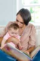 Mother kissing son while looking at picture book