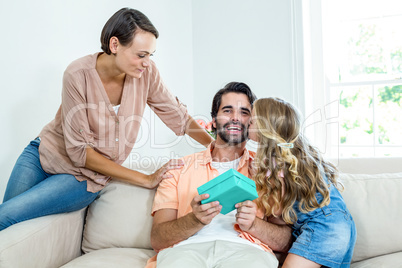 Daughter kissing father while mother sitting beside them