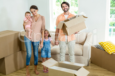 Happy family standing with boxes in new house