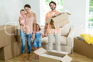 Happy family standing with boxes in new house