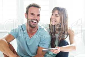 Couple with mobile phone on bed at home