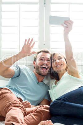 Cheerful couple taking selfie on bed