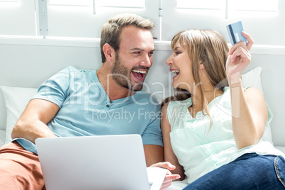 Couple using laptop on bed at home Couple using laptop on bed at home