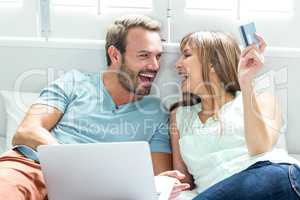 Couple using laptop on bed at home