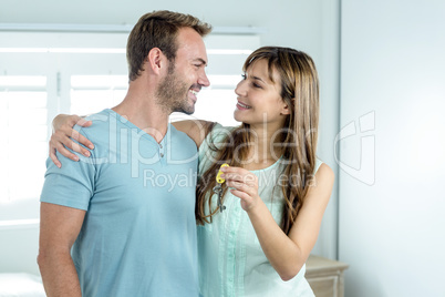 Couple with new house key embracing against window
