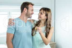 Couple with new house key embracing against window