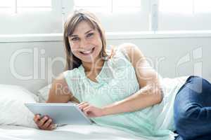 Beautiful woman smiling while using digital tablet on bed