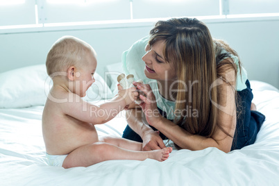 Mother playing with son on bed at home