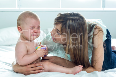 Woman with crying son on bed at home