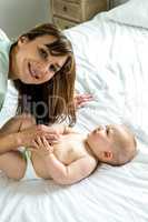 Happy mother playing with cute baby boy on bed