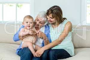Grandmother and mother playing with cute baby boy