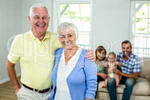 Happy senior couple with family sitting in background
