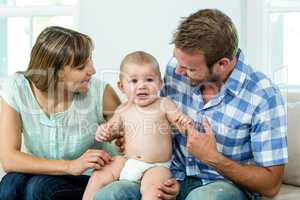 Parents with cute baby boy on sofa