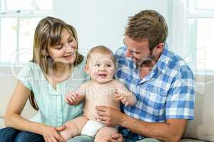 Parents playing with cute baby boy on sofa