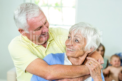 Happy couple embracing while family in background