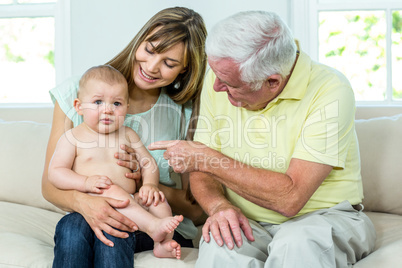 Grandfather and mother with baby boy on sofa