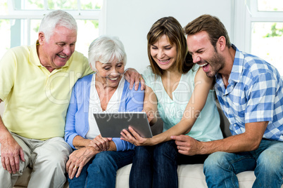 Family laughing while looking in digital tablet