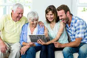 Family laughing while looking in digital tablet