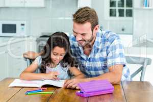 Father looking at daughter while drawing in book