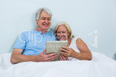 Senior couple using digital tablet while relaxing at home