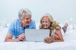 Happy senior couple using laptop while relaxing on bed