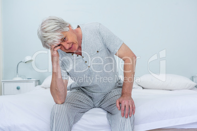 Senior man touching head while sitting at home