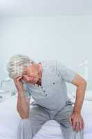 Senior man suffering from headache while sitting at home