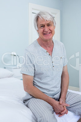 Portrait of senior man sitting on bed at home