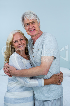 Portrait of happy senior couple hugging in bedroom