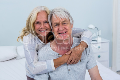 Portrait of happy senior couple hugging in bedroom