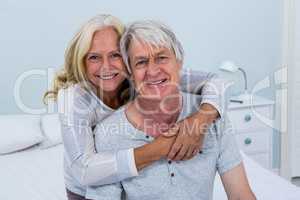 Portrait of happy senior couple hugging in bedroom