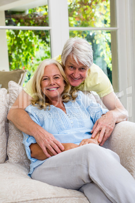 Happy senior couple sitting on sofa in living room at home