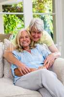 Happy senior couple sitting on sofa in living room at home