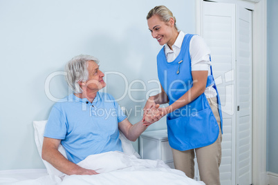 Nurse holding senior man hand in hospital