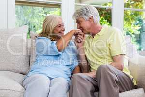 Romantic senior man kissing woman hand while sitting at home