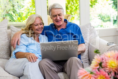 Senior couple using laptop while sitting on sofa