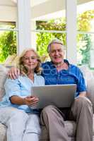 Portrait of senior couple holding laptop at home