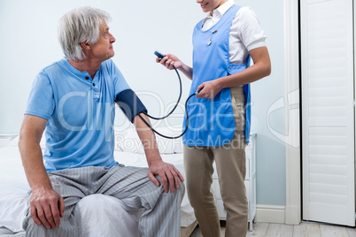 Nurse checking blood pressure of senior man at home
