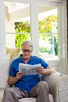 Senior man reading newspaper while sitting at home