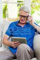 Senior man using mobile phone and digital tablet at home