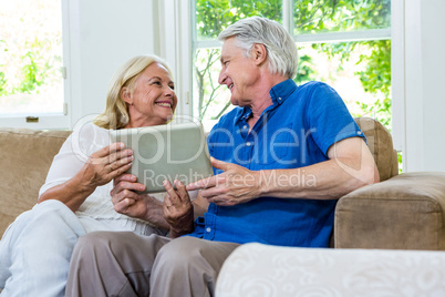 Cheerful senior couple using digital tablet at home