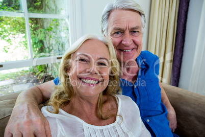 Smiling senior couple sitting in living room at home
