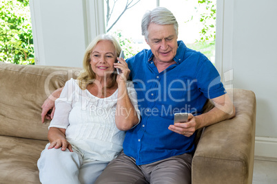 Senior couple using mobile phones while sitting at home